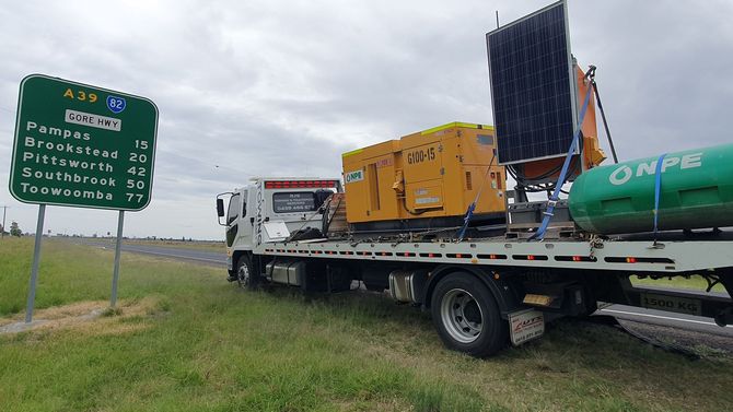 a long truck taking machinery on a wide road
