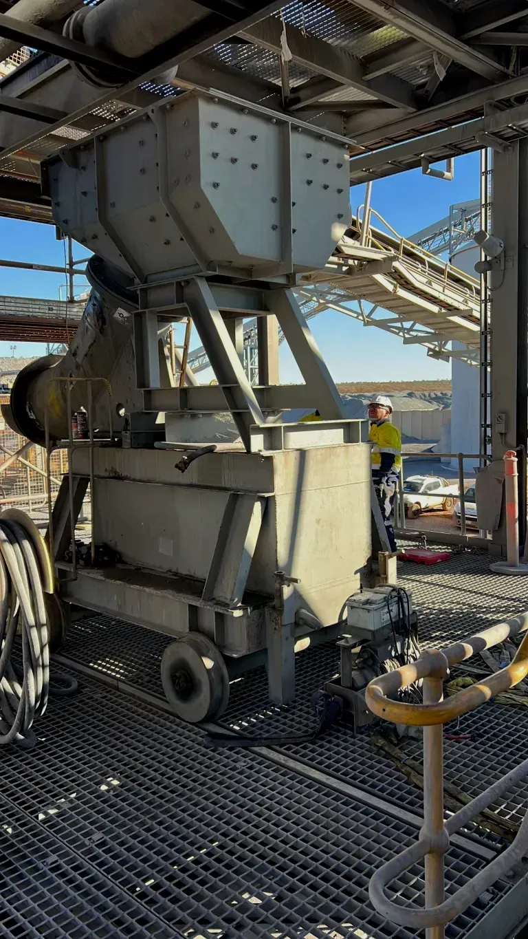 A man is standing next to a large machine in a factory.