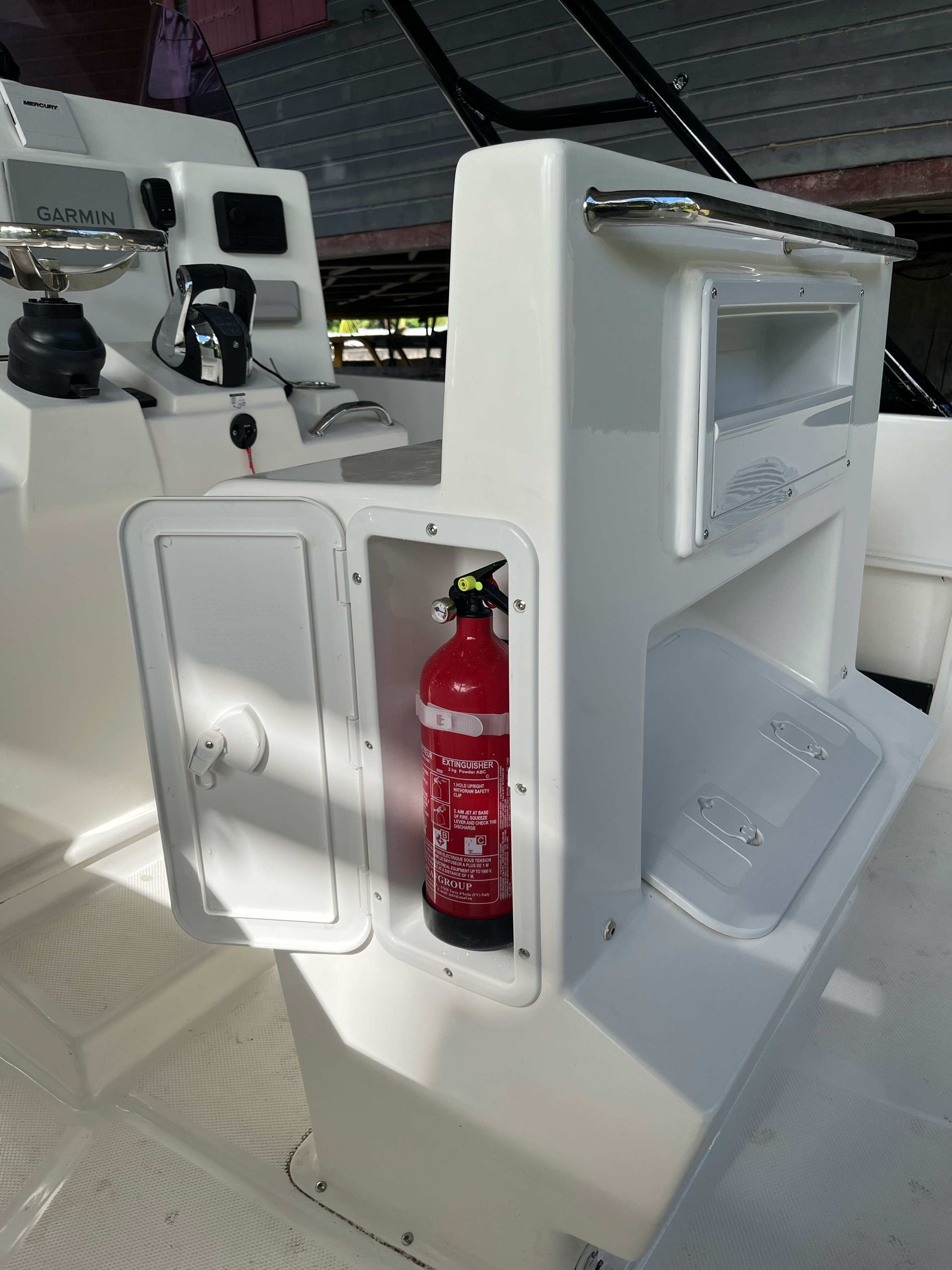 Cockpit de bateau blanc avec un compartiment de rangement intégré contenant un extincteur rouge.
