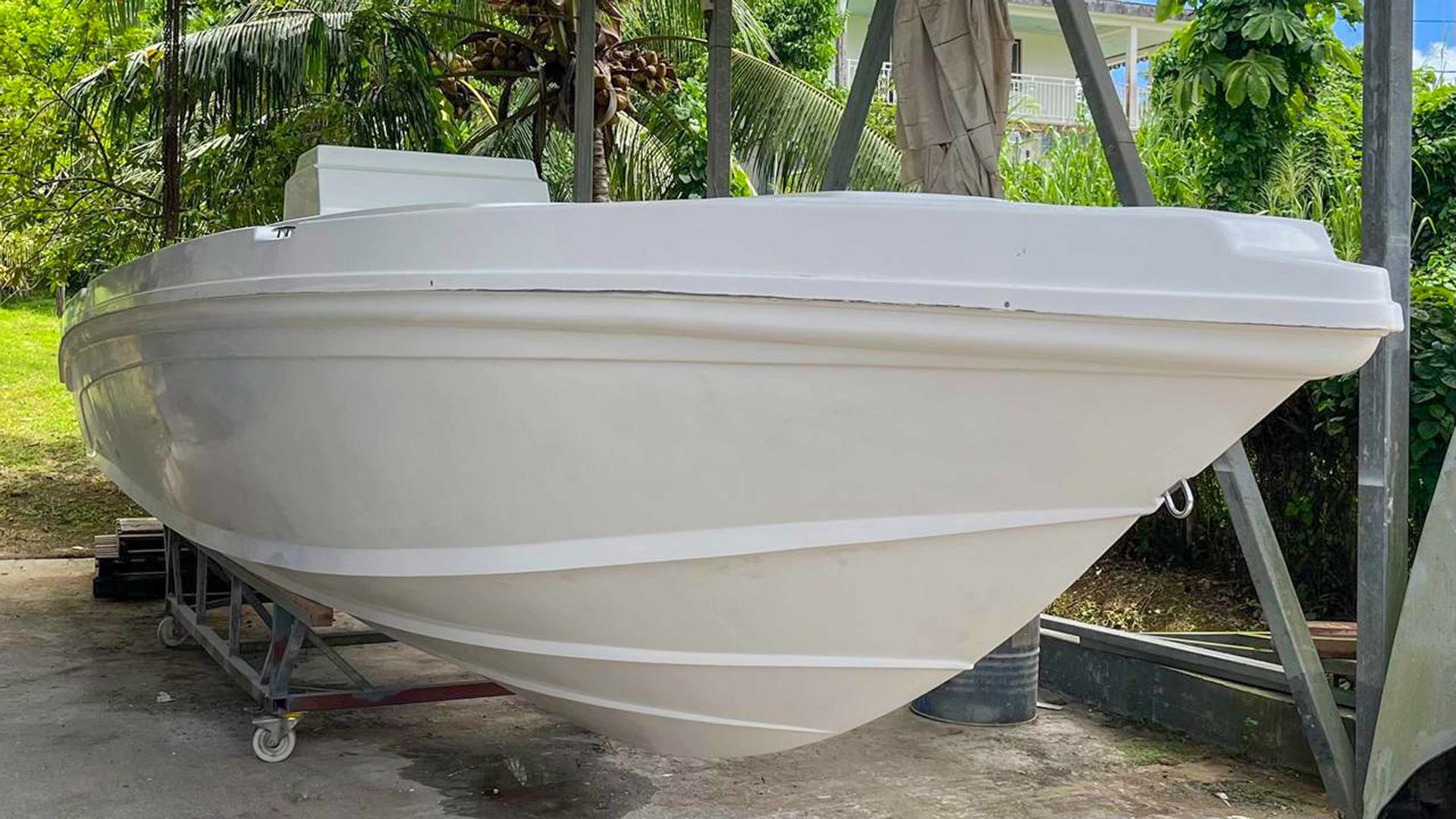 Coque de bateau blanche sur une remorque dans un espace extérieur ombragé