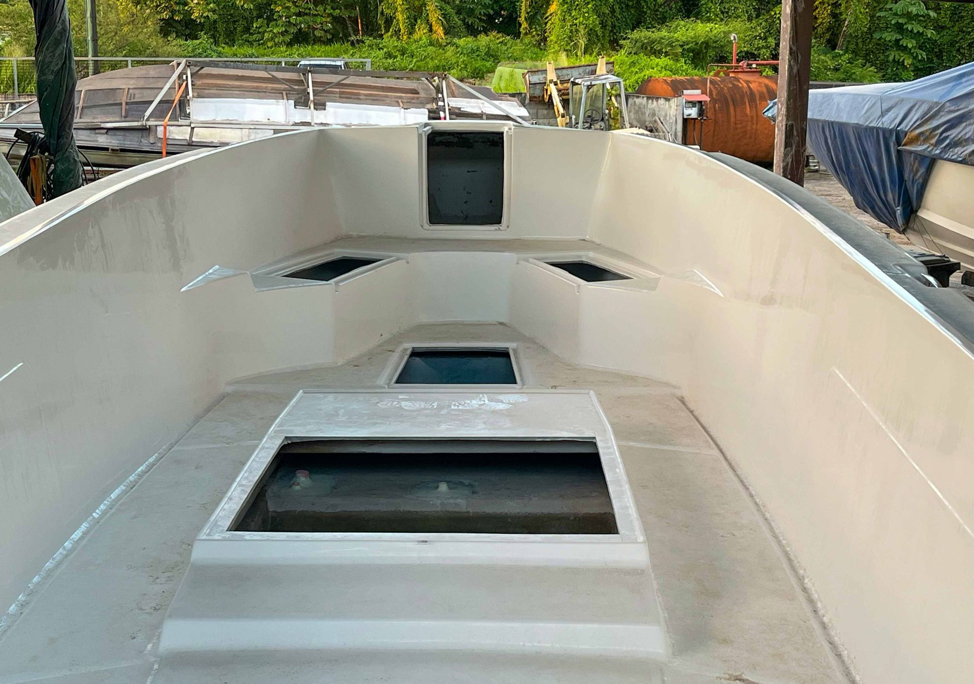 Intérieur de la cabine d'un voilier blanc avec écoutilles et fenêtre avant, vu du cockpit.