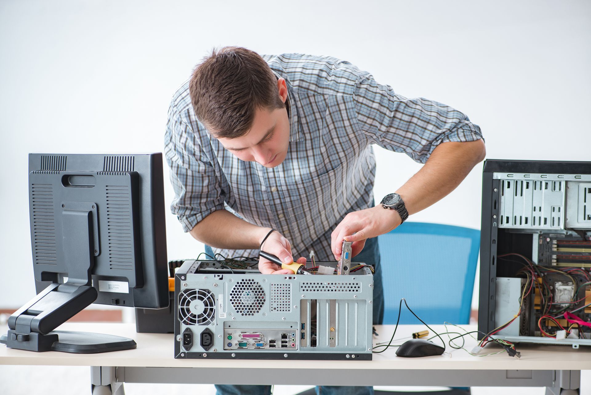 A technician focused on his work, fixing a desktop computer with tools A technician focused on his work, fixing a desktop computer with tools