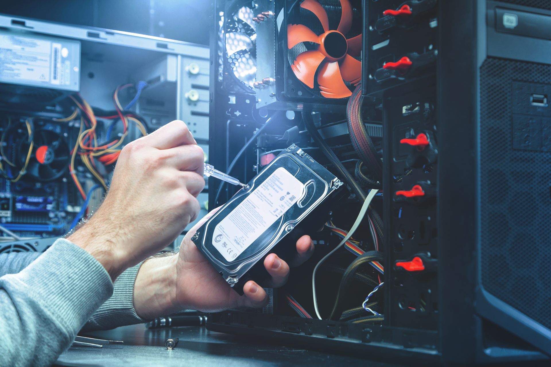 A technician repairs a computer, focusing on the hard drive, surrounded by tools A technician repairs a computer, focusing on the hard drive, surrounded by tools