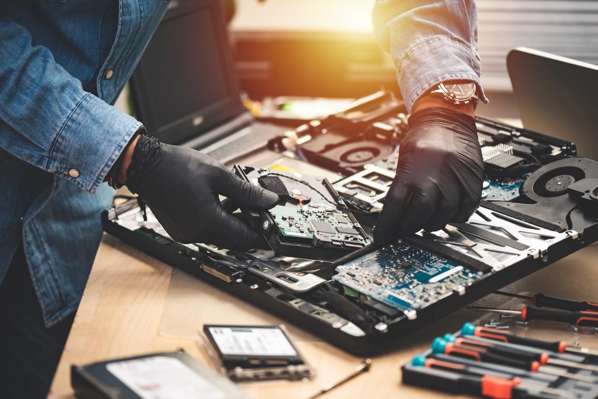 Technician repairing laptop motherboard and hard drive at computer service center. Technician repairing laptop motherboard and hard drive at computer service center.