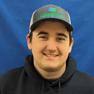 A man wearing a hat and a hoodie is smiling for the camera.