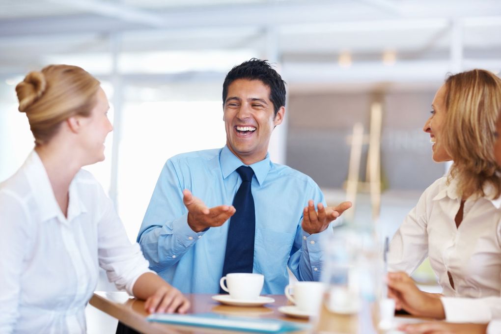 A group of people are sitting around a table having a conversation.