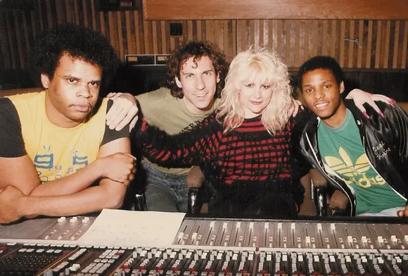 A group of people posing for a picture with one wearing an adidas shirt