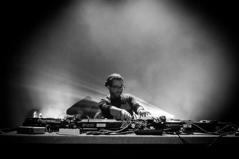 A man is playing a dj set on a stage in a black and white photo.
