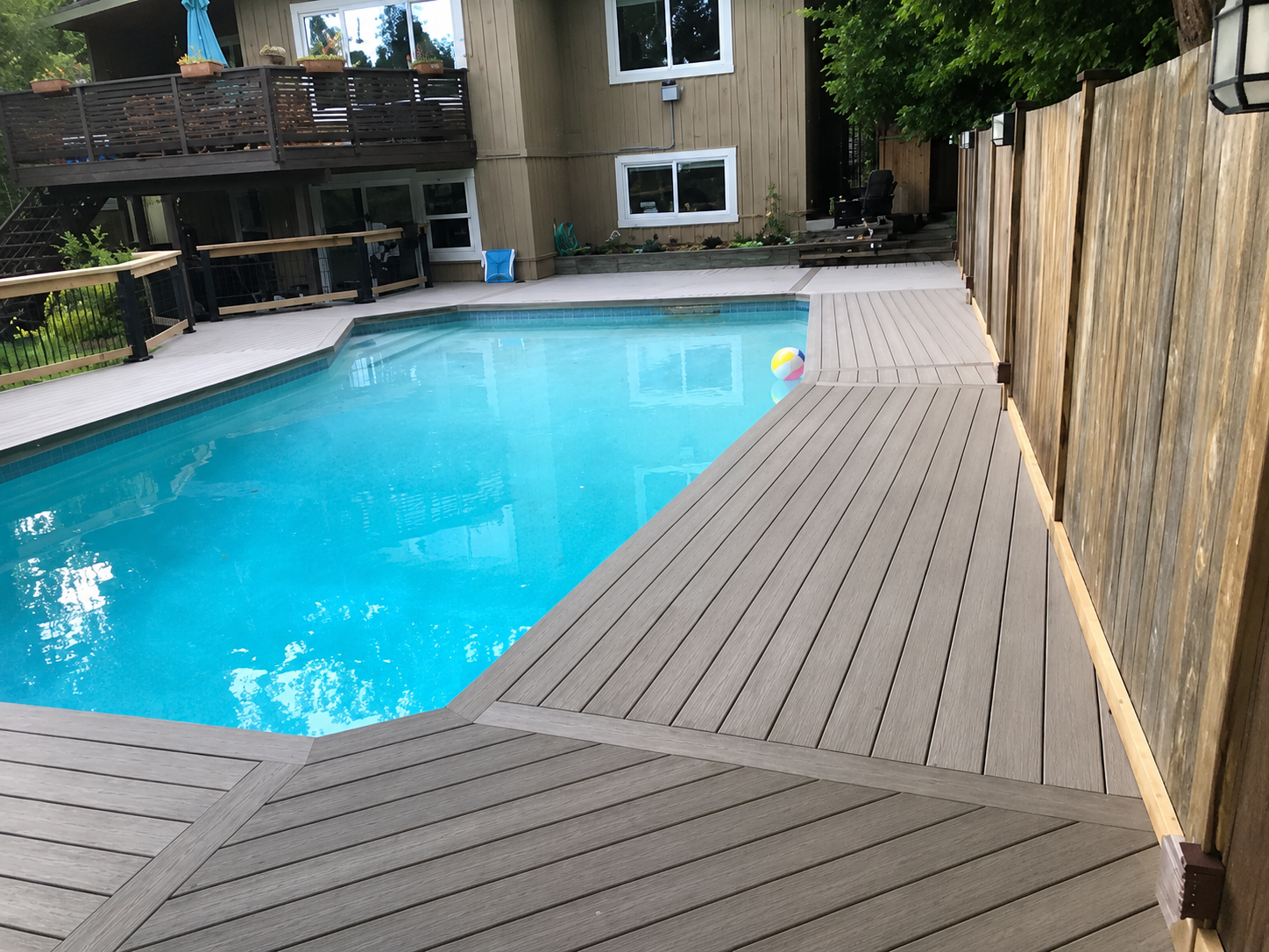 Backyard pool with turquoise water and a wooden deck along the right side