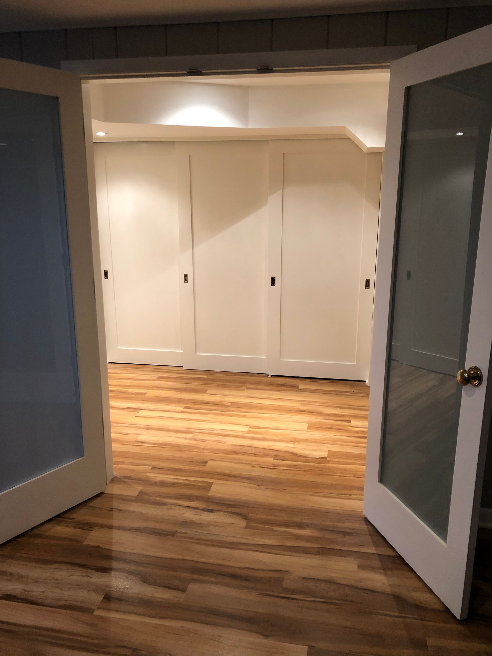 Open double doors to a room with wood flooring and white closet doors.