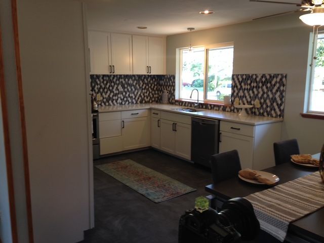 Modern kitchen with white cabinets, mosaic backsplash, island seating, and a window over the sink