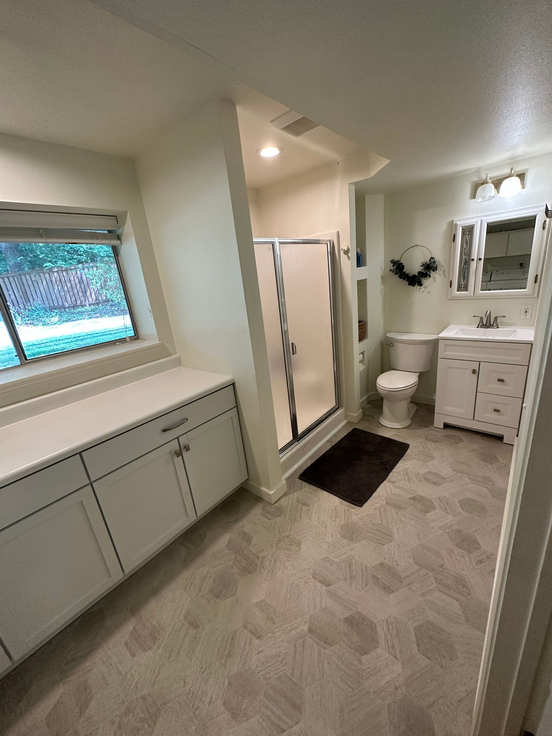 Bright bathroom with tiled floor, shower curtain, toilet, sink vanity, and window
