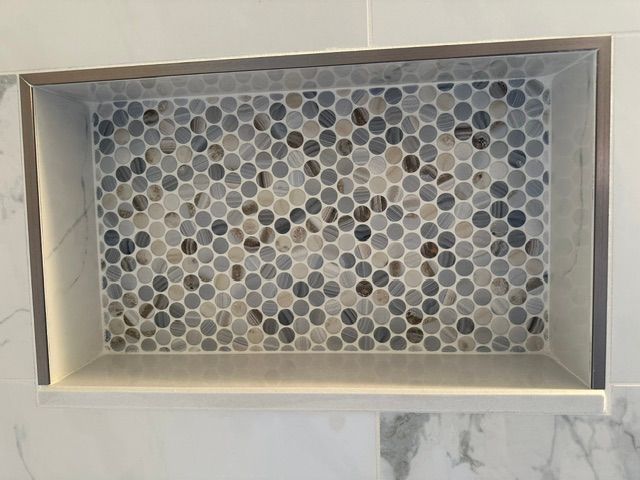 Rectangular tray of small round gray, white, and tan mosaic tiles on a countertop