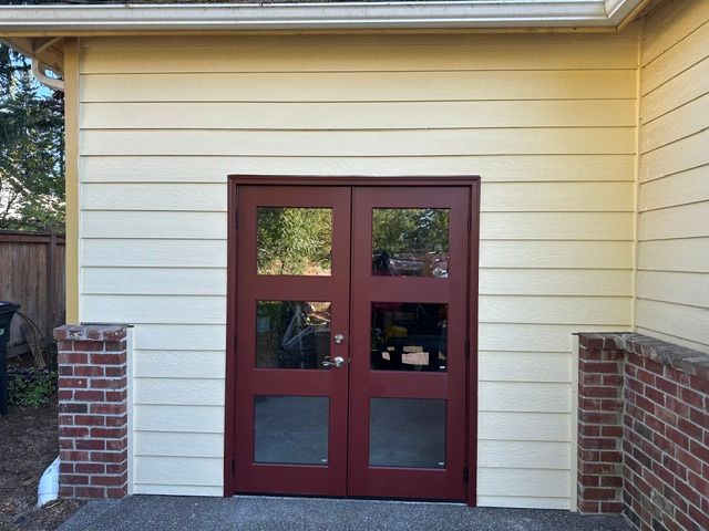 Red double front door with four windows in a cream-sided brick house exterior