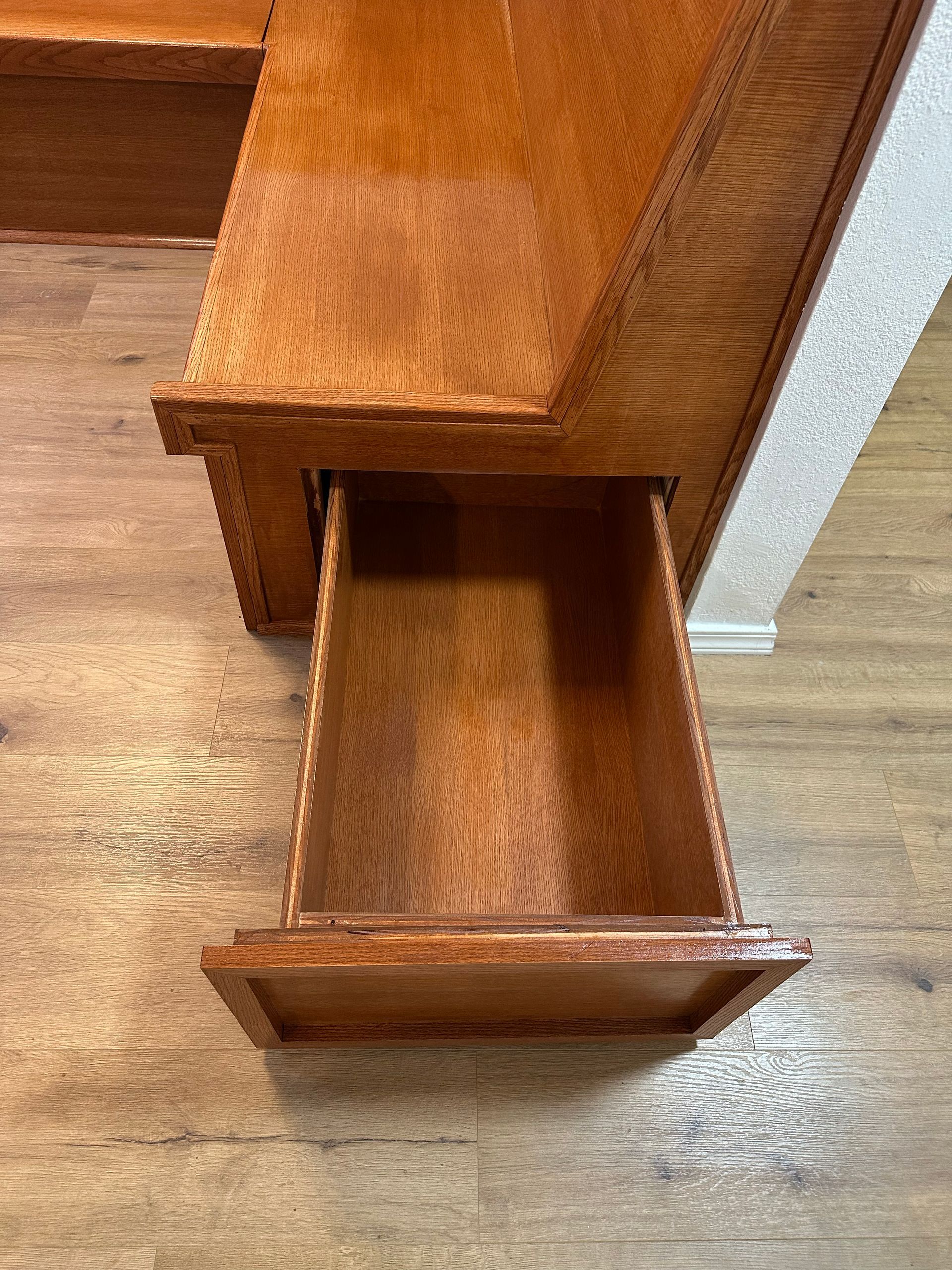 Open wooden drawer with a lower pull-out compartment beside a stair tread.