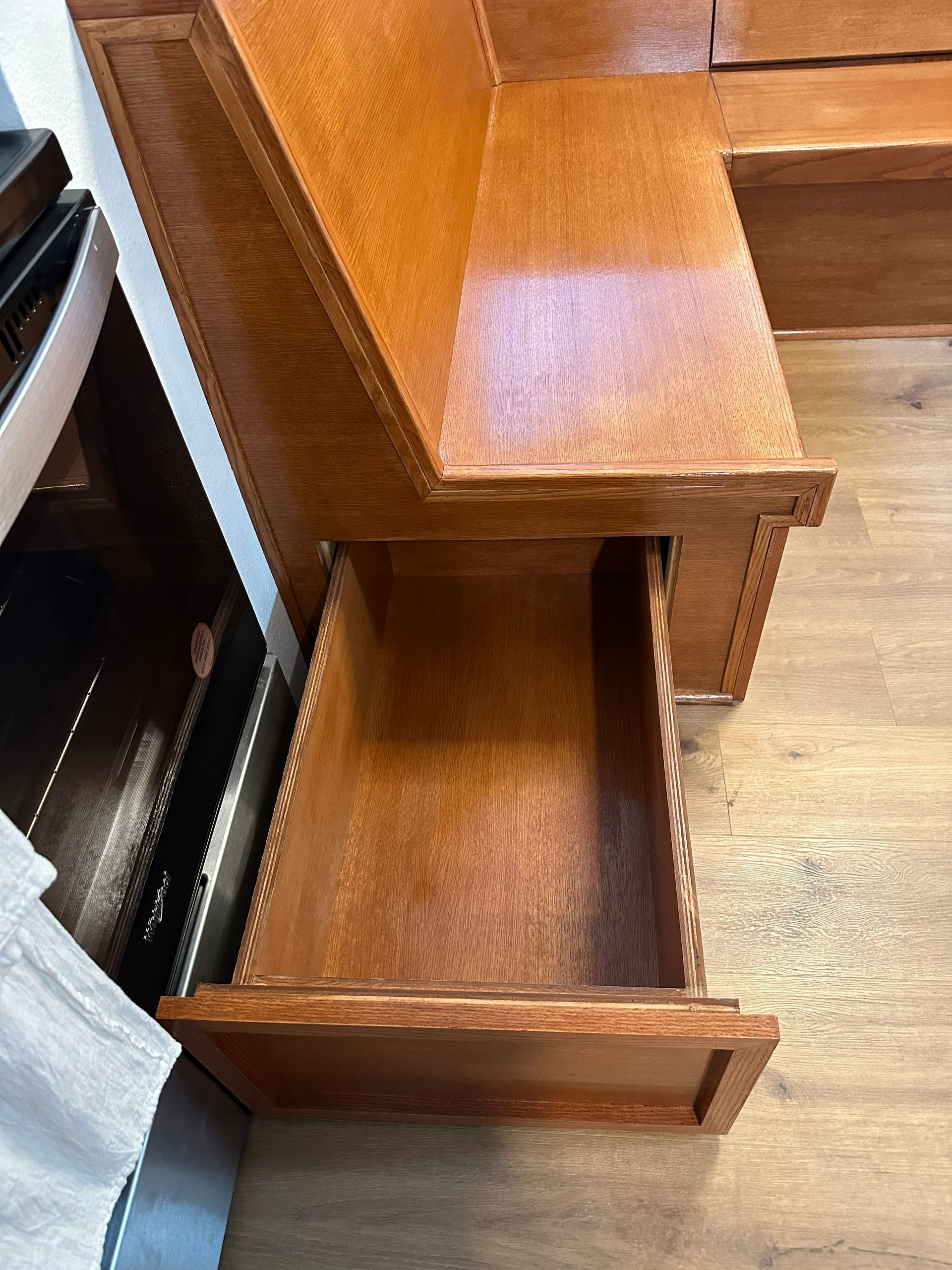Wooden desk with an open lower drawer and a second drawer above it on a hardwood floor