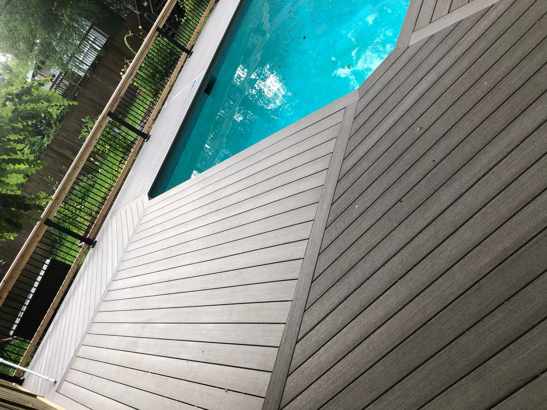 Pool deck beside turquoise water, with gray slatted and dark wooden surfaces.