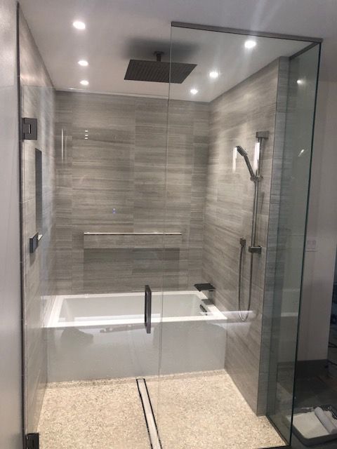 Modern tiled bathroom with a walk-in glass shower, bathtub, and rain showerhead