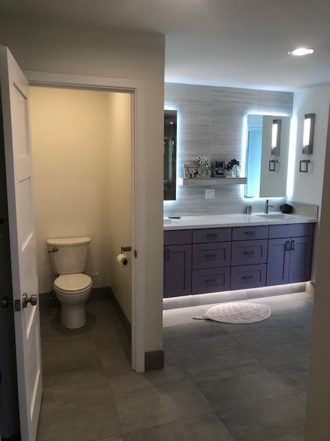 Bathroom interior with toilet nook, vanity, mirror, and gray tile flooring