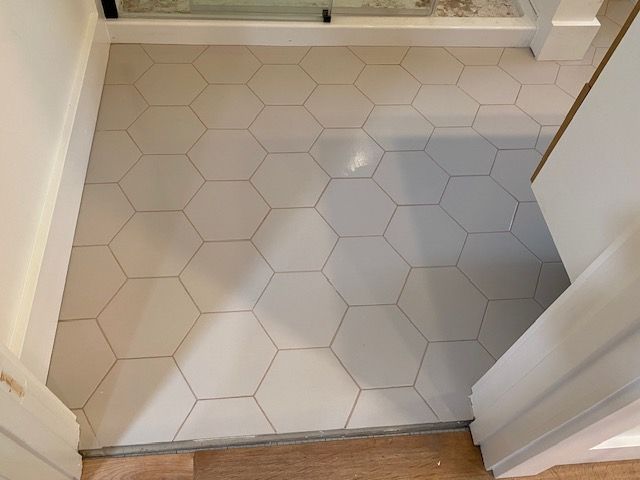 White hexagon tile floor in a small bathroom doorway with a threshold and vanity edge visible