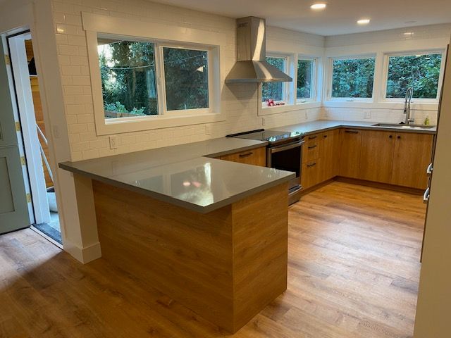 Bright modern kitchen with wood cabinets, gray countertops, island, and large windows