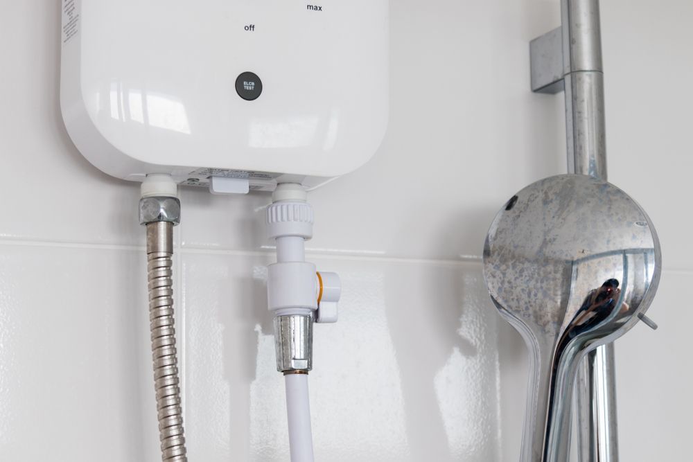 Bathroom wall with a white water heater, flexible hose, shutoff valve, and shower head.