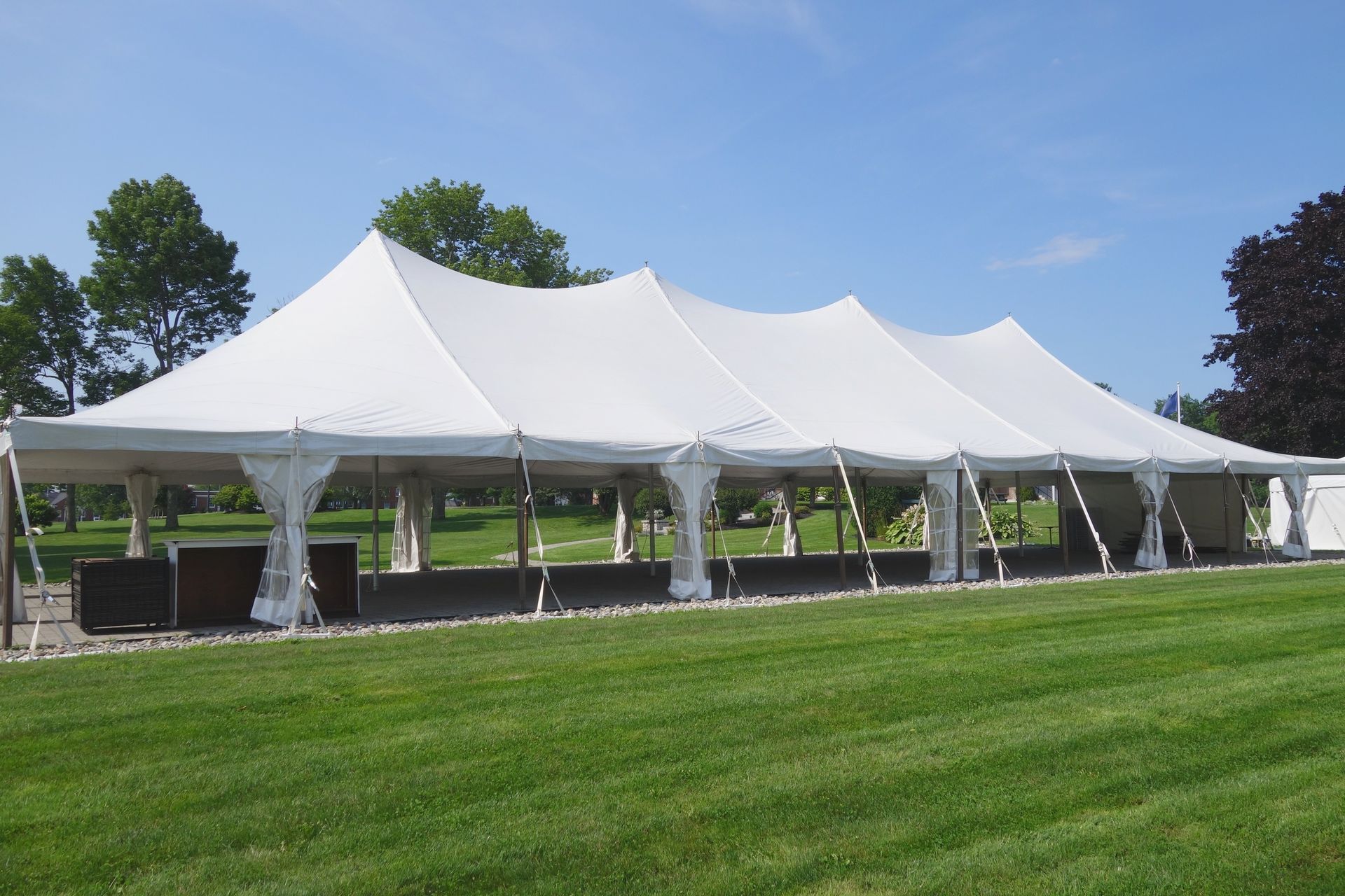 Large white pole tent set up on a grassy lawn, providing spacious outdoor shelter.