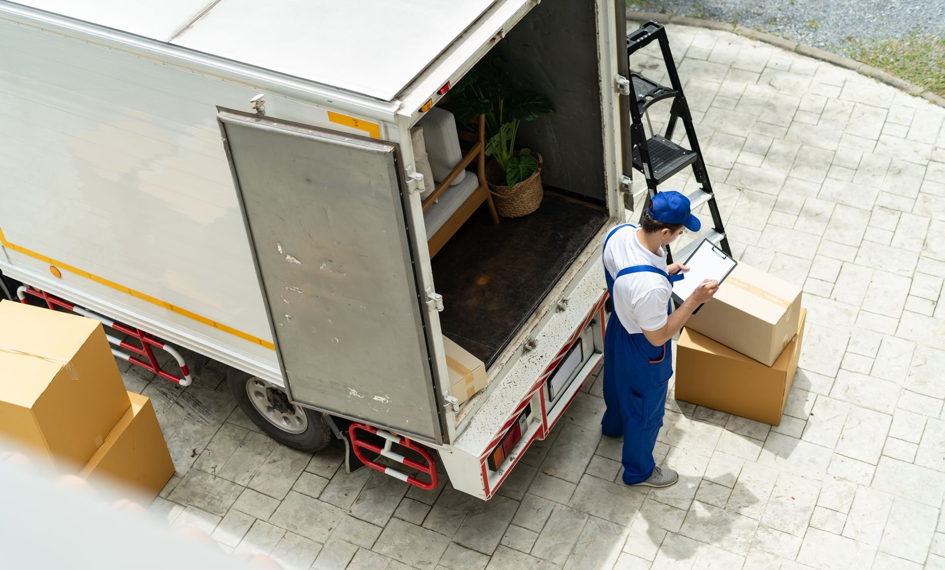 Residential movers unloading boxes and furniture from a moving truck parked outside a home.