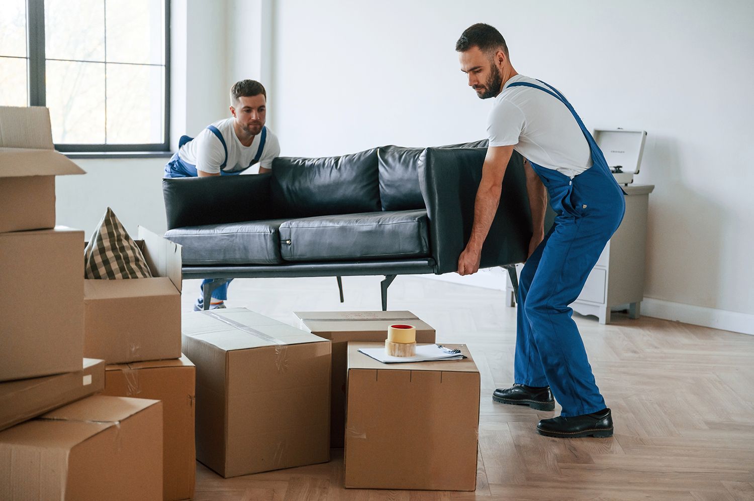 Two movers are carrying a couch. Two movers are carrying a couch.