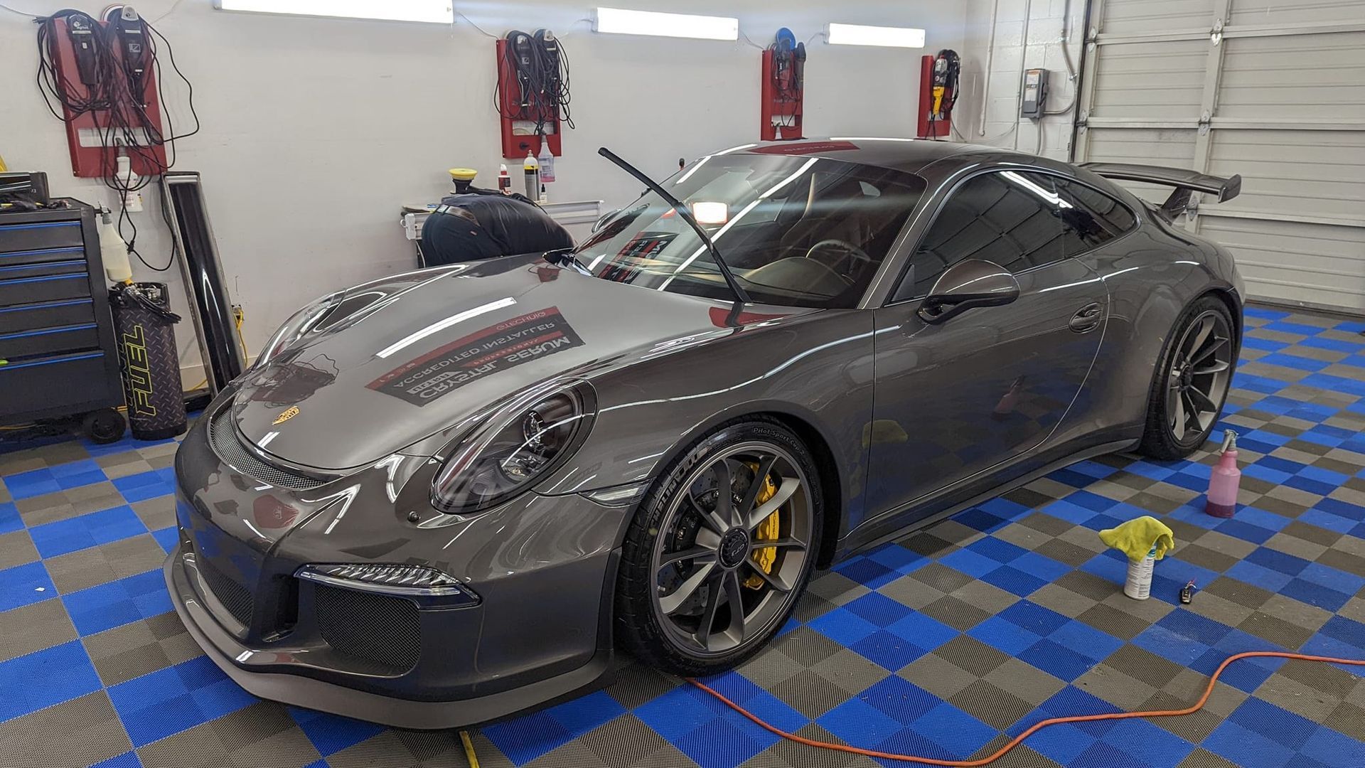A gray porsche 911 gt3 rs is parked in a garage.