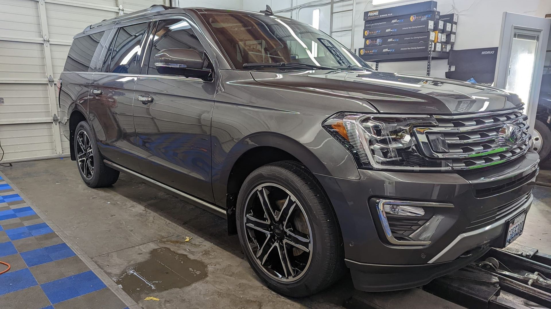 A gray ford expedition is parked in a garage.