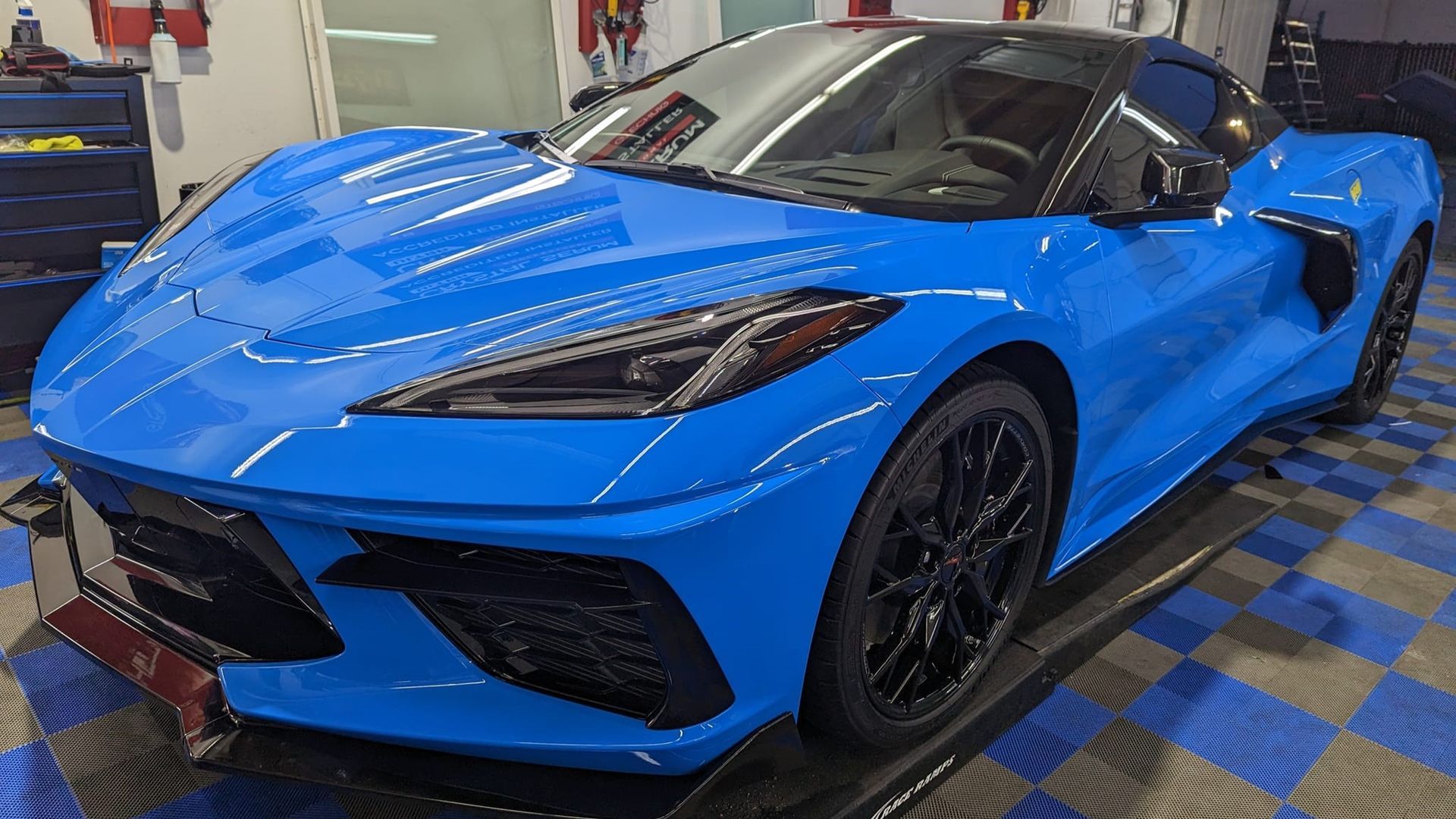 A blue sports car is parked on a lift in a garage.