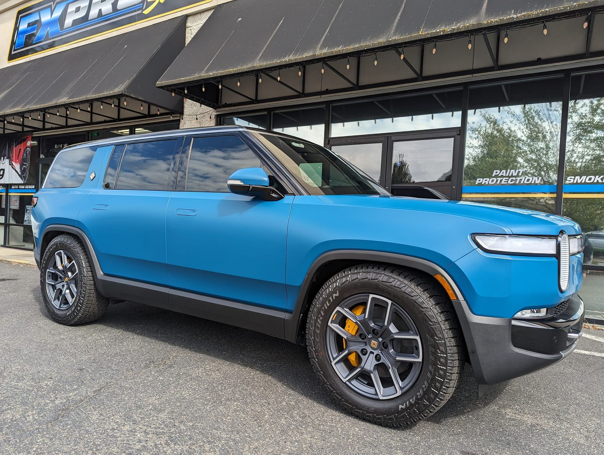 A blue suv is parked in front of a building.