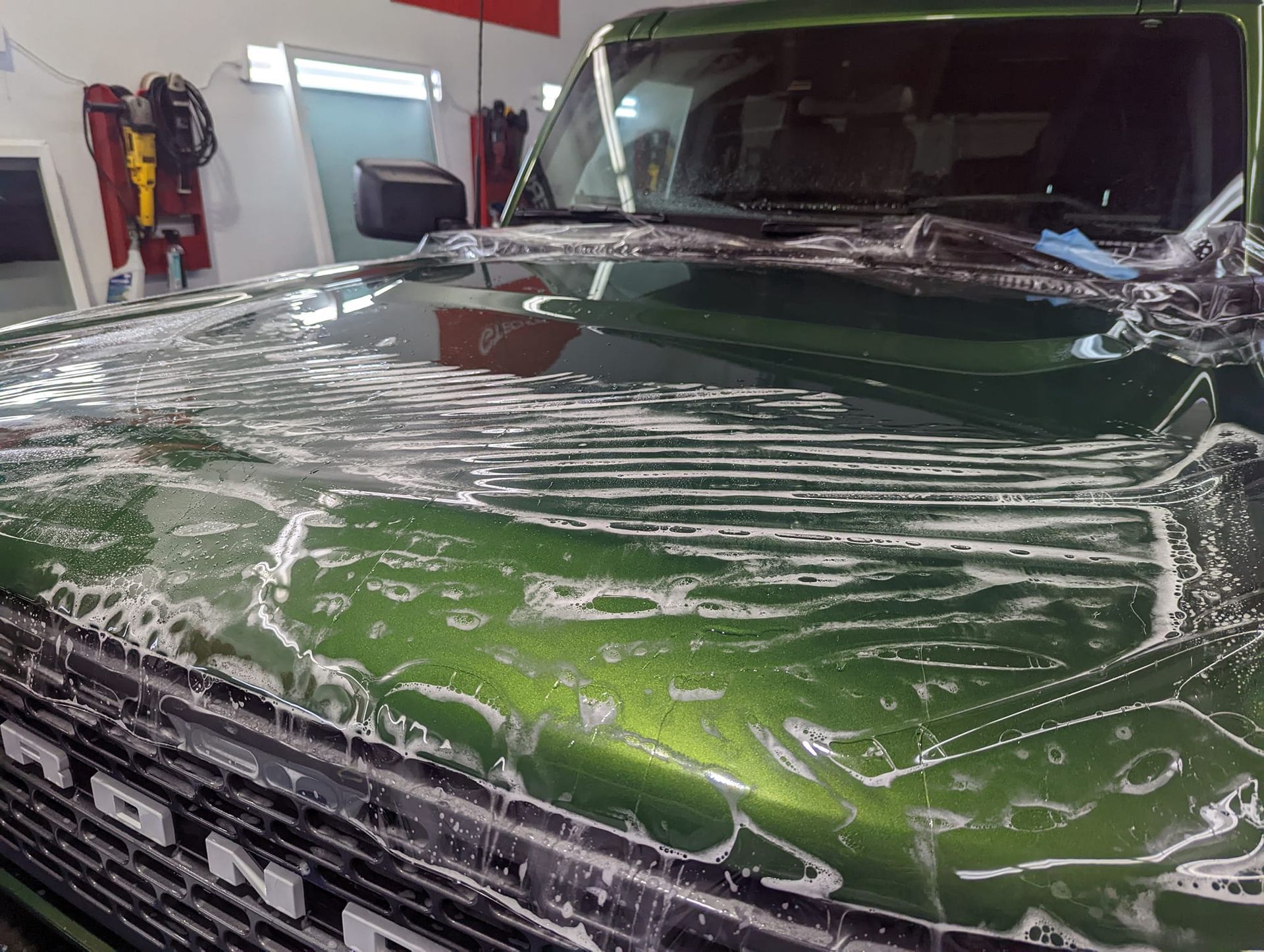 A green ford truck is being washed in a garage.