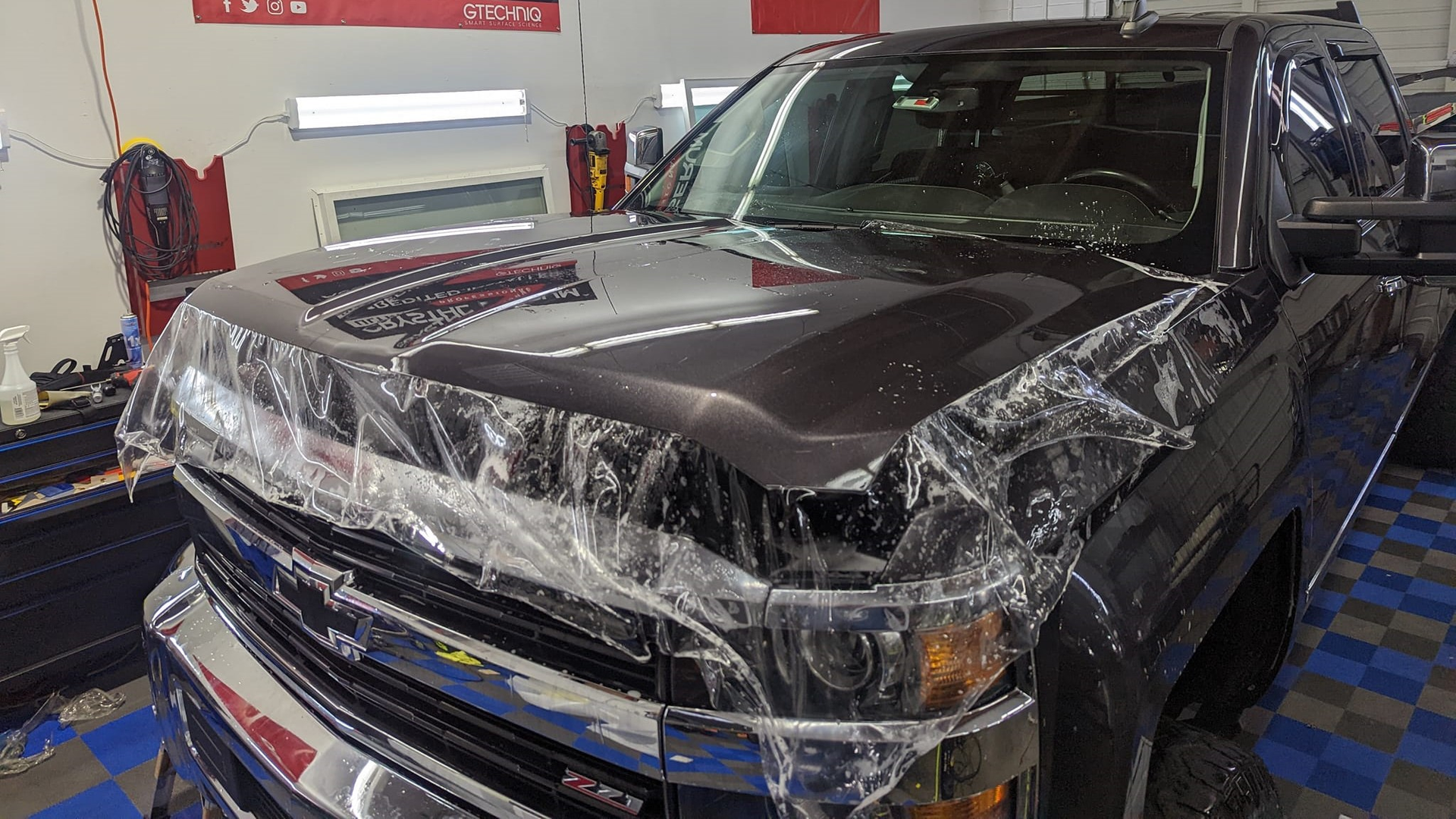 A truck is covered in plastic wrap in a garage.