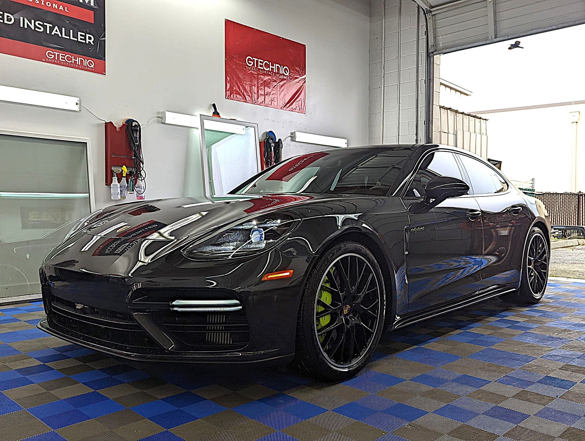 A black porsche panamera turbo s is parked in a garage.
