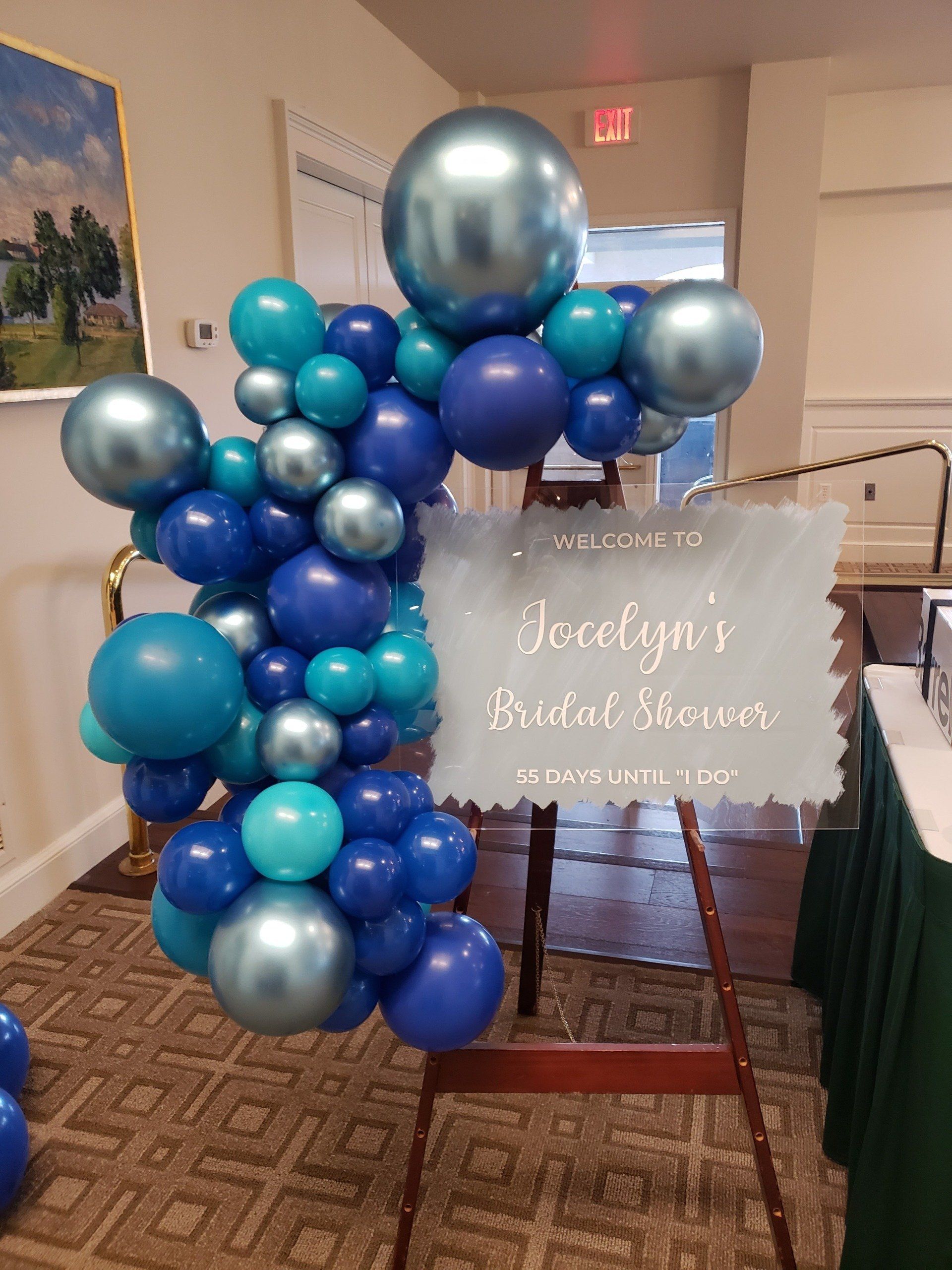 Teal, blue and metallic organic garland attached to sign.