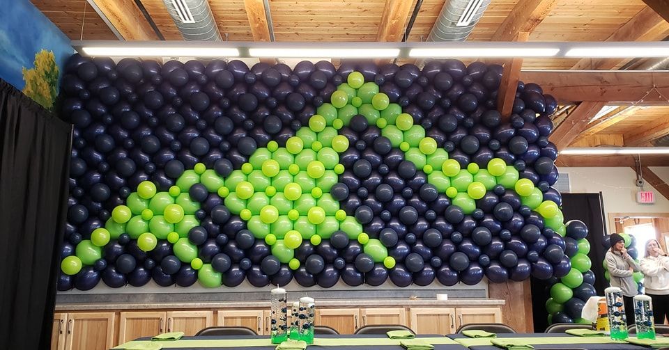 Navy balloon wall with neon green outline of mountain rainge. 