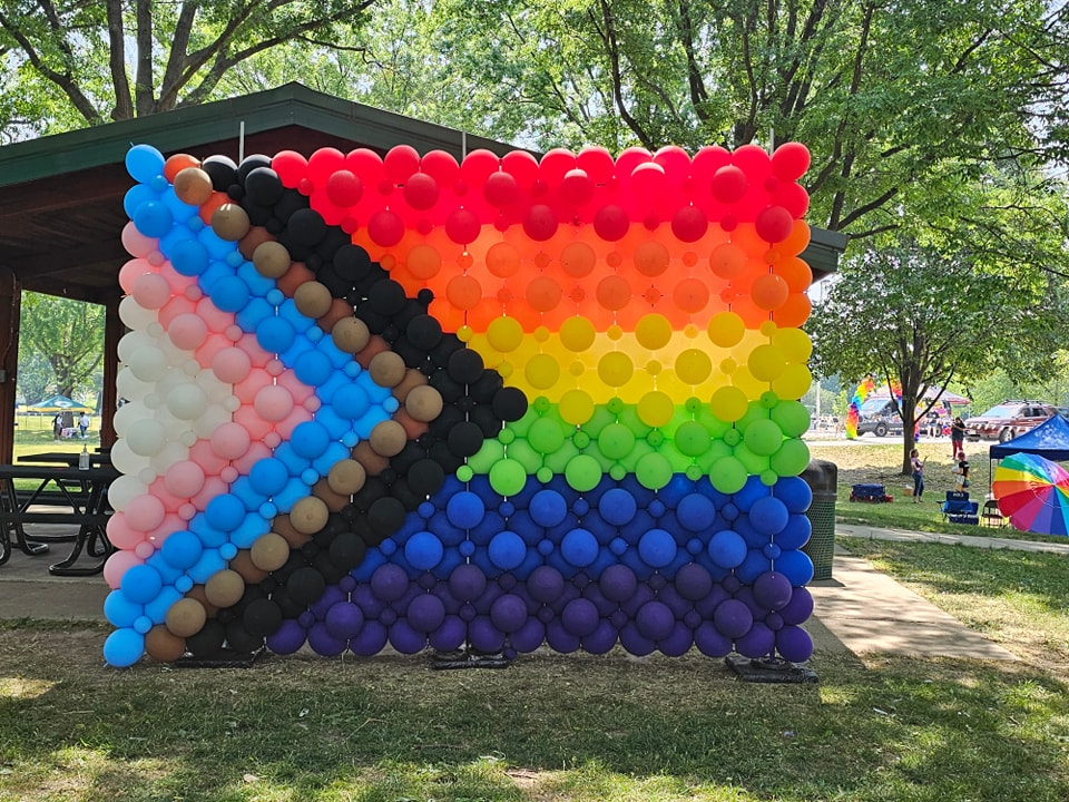 Pride flag balloon wall. Pride colors, rainbow, white, pink, light blue, brown and black. 