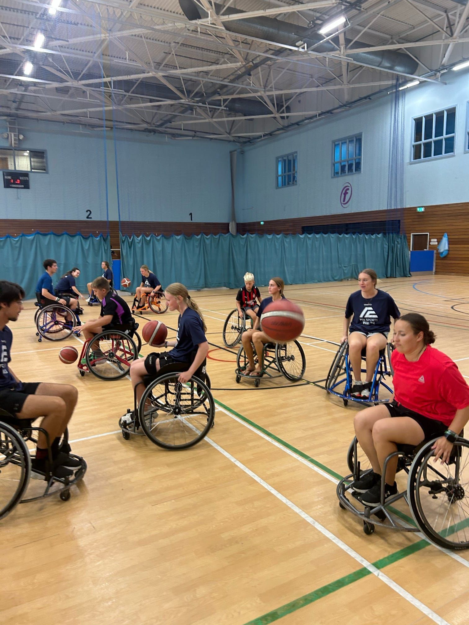 A group of students in wheelchairs practice wheelchair basketball.