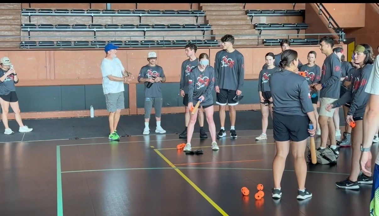 A team of people in matching shirts play blind baseball.