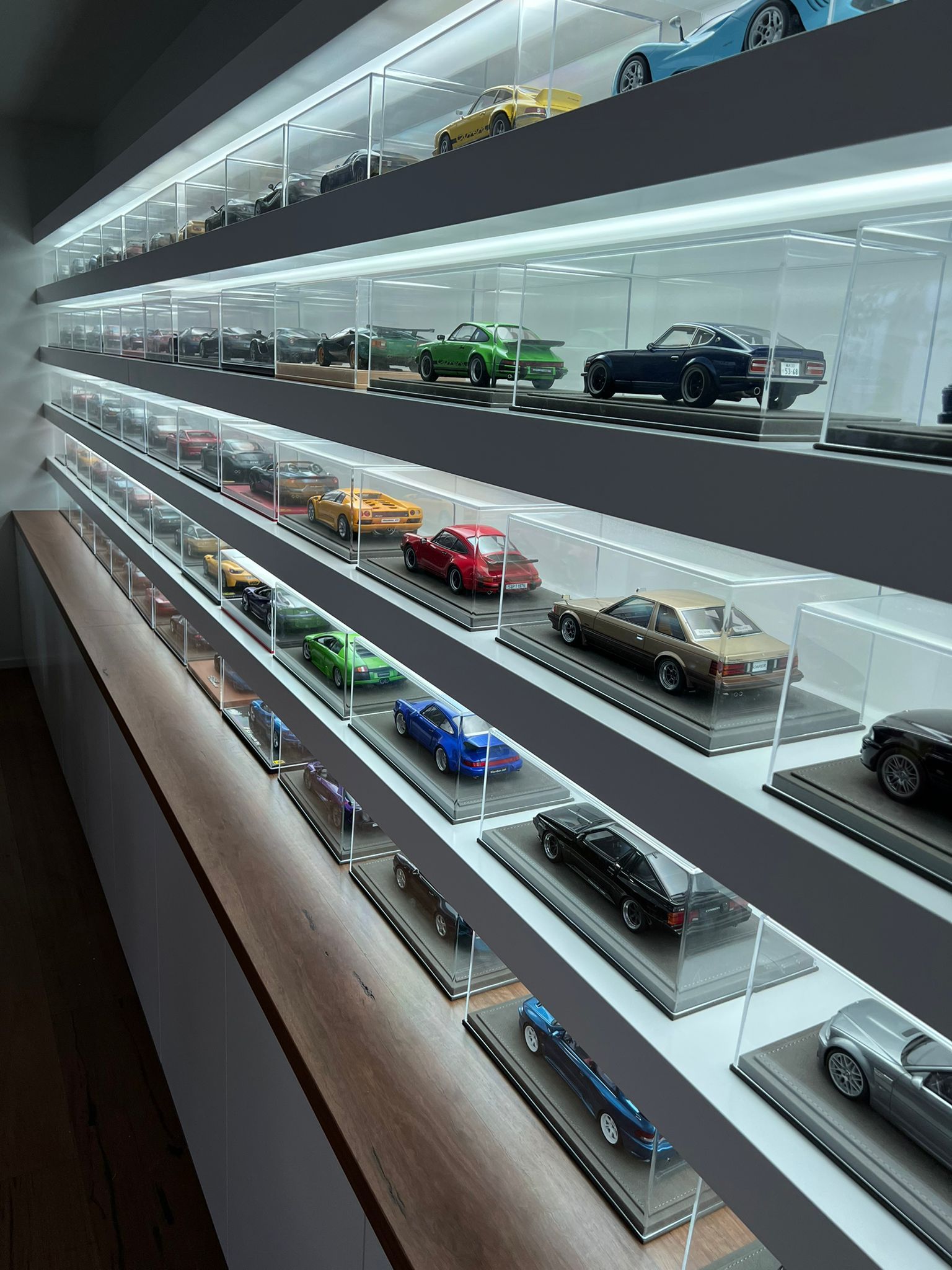 Model cars displayed in lighted glass shelves along a wall.