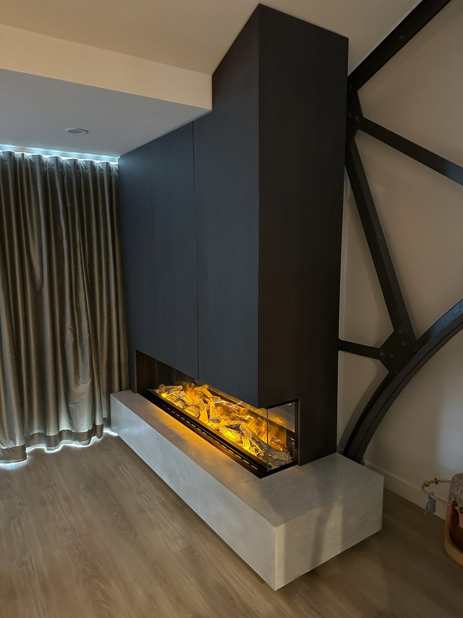 Modern fireplace with black surround, concrete base, and glowing faux flames.