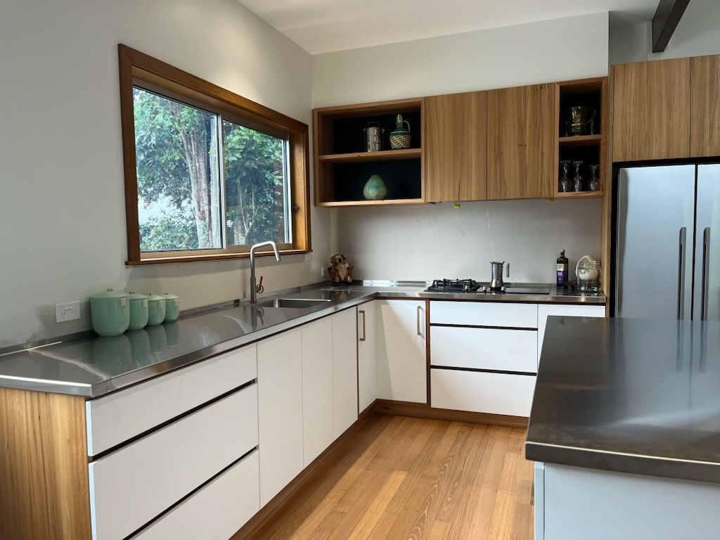 Modern kitchen with white cabinets, stainless steel countertops, and bamboo accents.