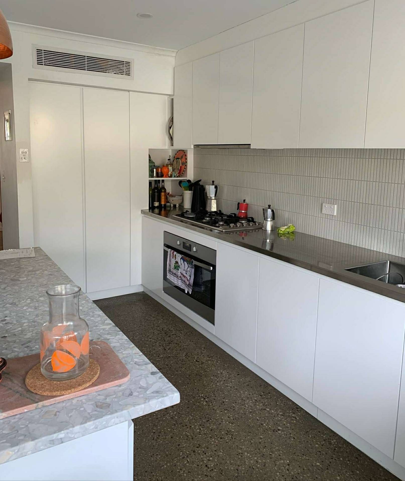 White kitchen with cabinets, stove, sink, and island with countertop.