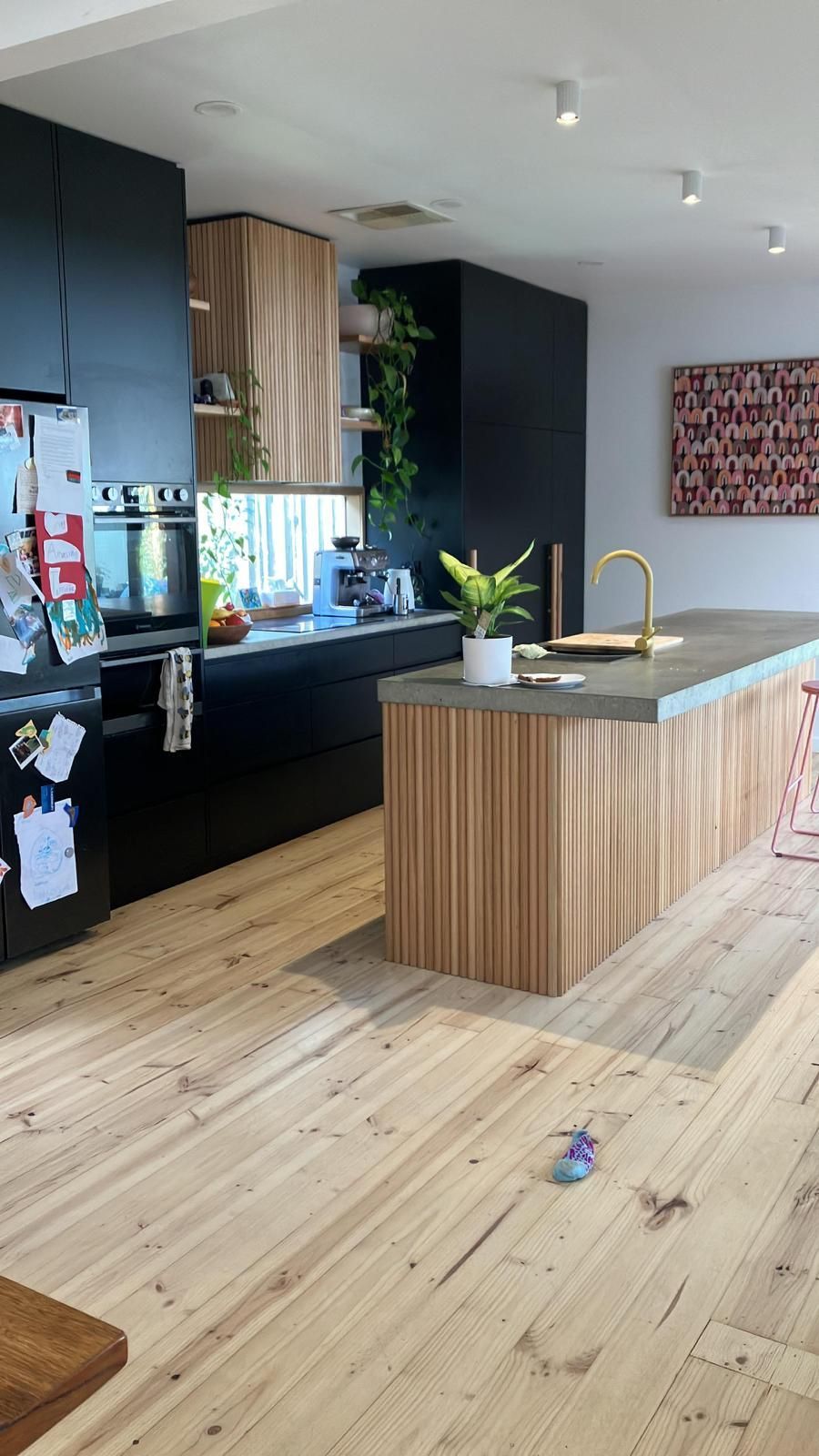 Modern kitchen with black cabinets, wooden accents, and a central island.