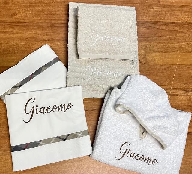 Confezioni regalo personalizzate e asciugamani su una superficie in legno, con etichetta “Giacomo”