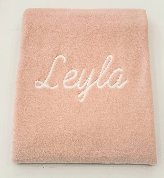 Asciugamano rosa piegato con il nome “Leyla” ricamato in corsivo bianco