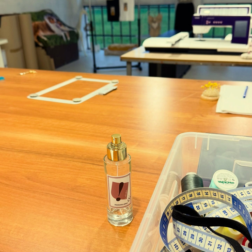Scrivania con una piccola boccetta di profumo, un metro a nastro e materiali per lavori manuali in un'aula o in uno spazio di lavoro.