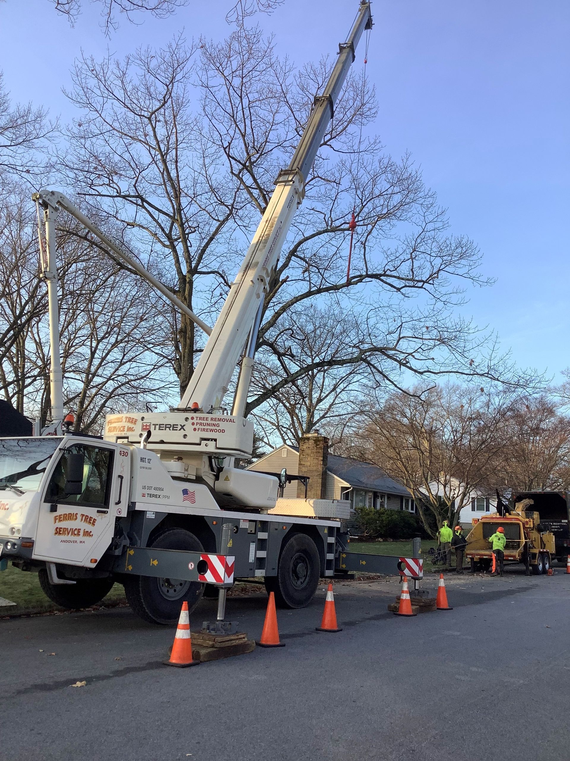 A white truck with a crane on top of it is parked on the side of the road.